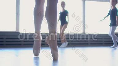 年轻的芭蕾舞演员在训练中跳跃。 芭蕾舞学校。 双脚特写。 穿着黑色芭蕾舞裙的芭蕾舞裙的美丽芭蕾舞演员